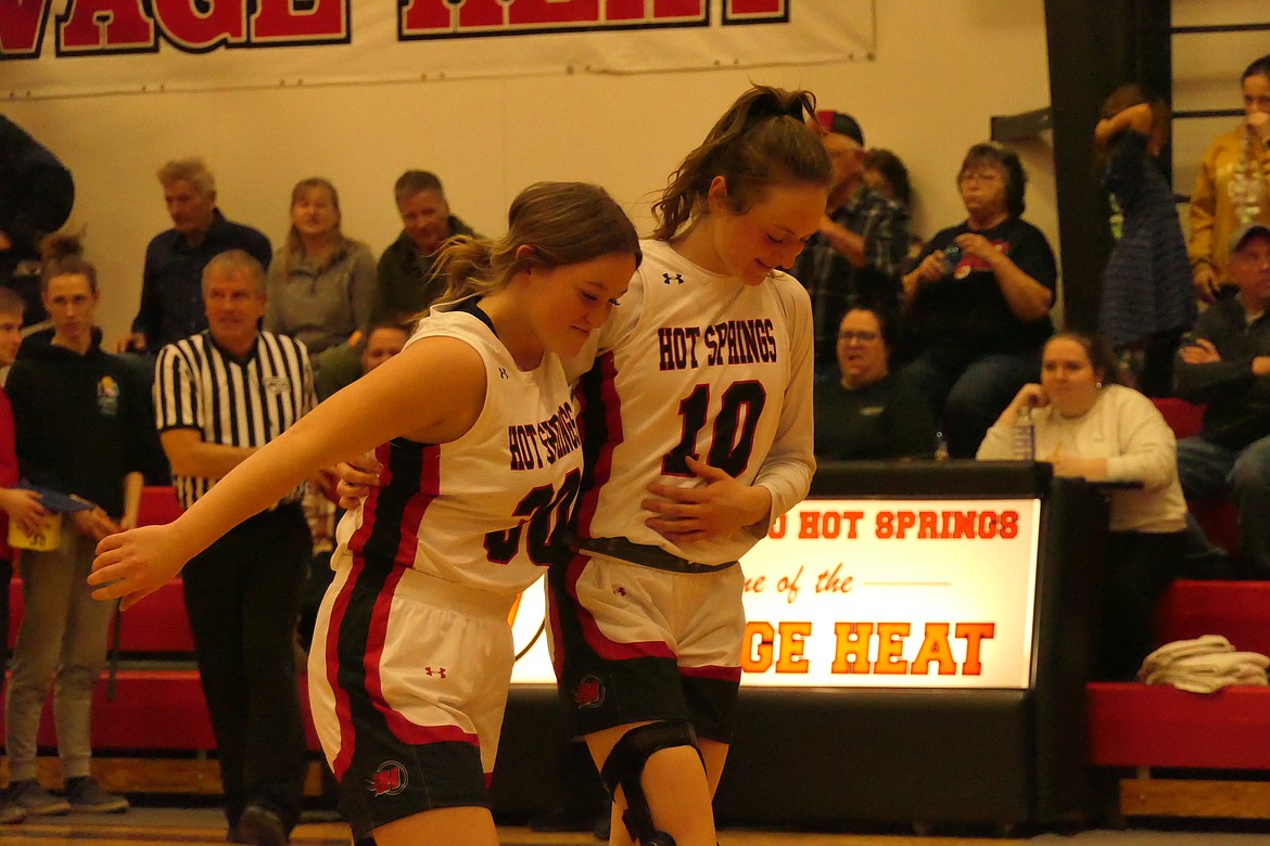 Hot Springs senior Katelyn Christensen helps fellow senior Moira Lonergan to her spot under the basket where the injured Lonergan sank an uncontested ceremonial basket to open the Lady Savage Heat's game with Plains this past Tuesday night.  (Chuck Bandel/Valley Press)