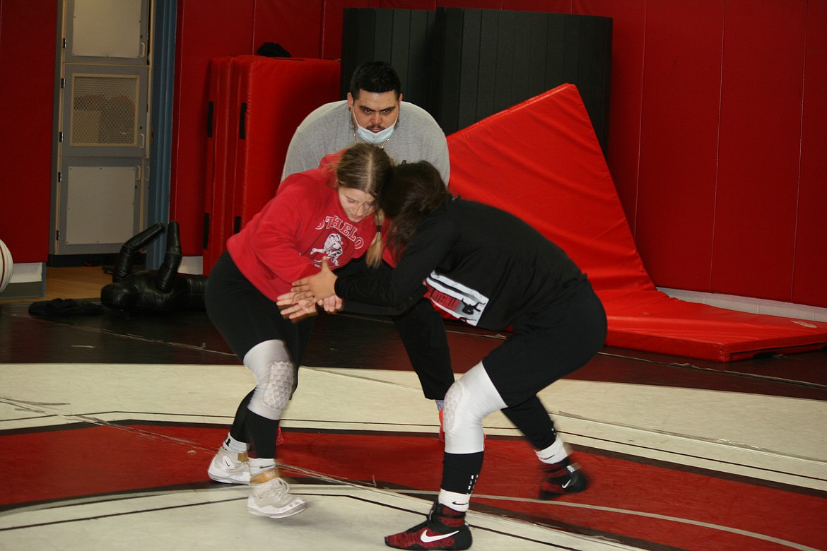 Othello High School wrestlers Lexi Monday (left foreground) and Grace Rocha (right foreground) work on their technique during practice Jan. 13 while assistant coach Mark De La Rosa supervises. Monday advanced to the state tournament Feb. 12.