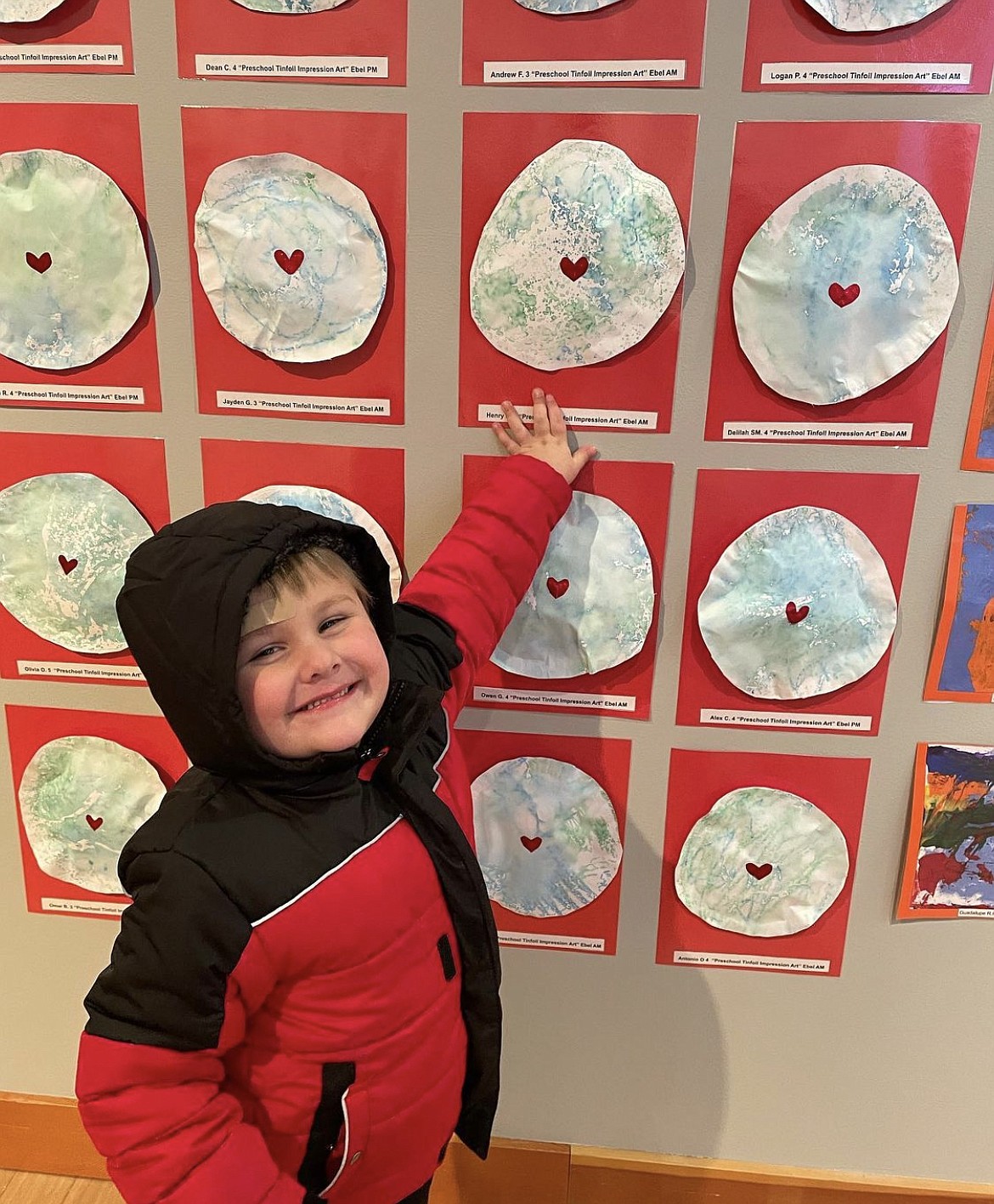 Moses Lake preschooler Henry Duvall grins broadly at the Moses Lake School District’s preschool art show. Students like Duvall worked hard to put together artwork reflecting the theme: KINDNESS MATTERS!