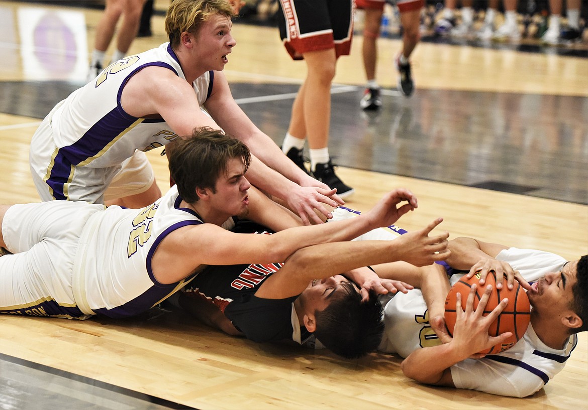 Nikolai Figaro comes up with a loose ball during a scramble on the floor that included teammates Colton Graham (32) and Trent Wilson. (Scot Heisel/Lake County Leader)