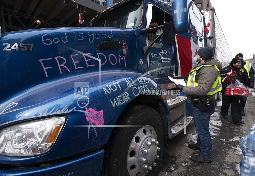 Police speak with a driver as they distribute notices to protesters, Wednesday, Feb. 16, 2022 in Ottawa. Ottawa’s police chief was ousted Tuesday amid criticism of his inaction against the trucker protests that have paralyzed Canada's capital for over two weeks, while the number of blockades maintained by demonstrators at the U.S. border dropped to just one. (Adrian Wyld /The Canadian Press via AP)