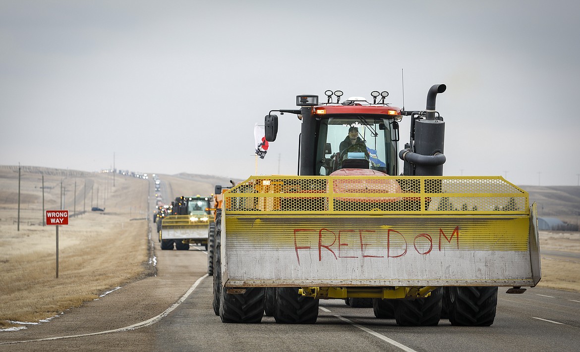 Anti-COVID-19 vaccine mandate demonstrators leave in a truck convoy after blocking the highway at the busy U.S. border crossing in Coutts, Alberta, Tuesday, Feb. 15, 2022. (Jeff McIntosh/The Canadian Press via AP)