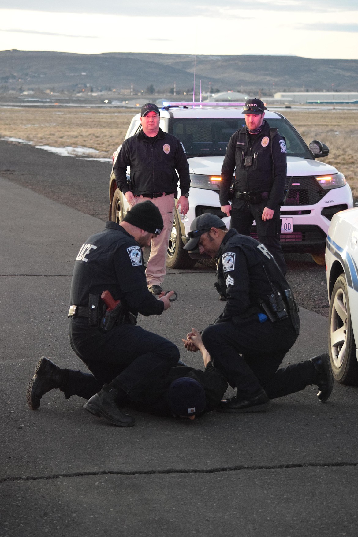 Quincy Police Officer Brad Poldervart (left) and Sgt. Jorge Trujillo (right) arrest a “suspect” played by Quincy Animal Shelter assistant Daniel Reyes during training at the Ephrata Airport on Tuesday.