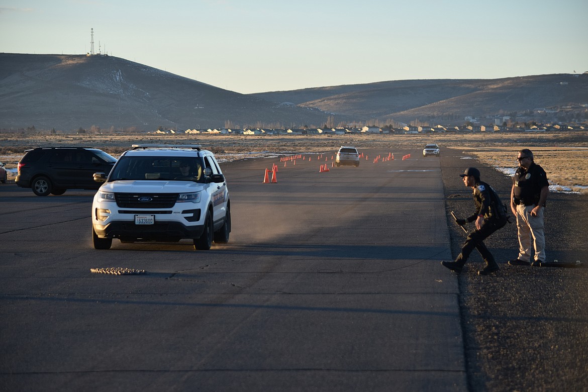 Quincy Police Officer Jerry Martinez throws a spike strip — spikeless for training purposes — in front of a speeding vehicle as Officer Sal Mancini watches.