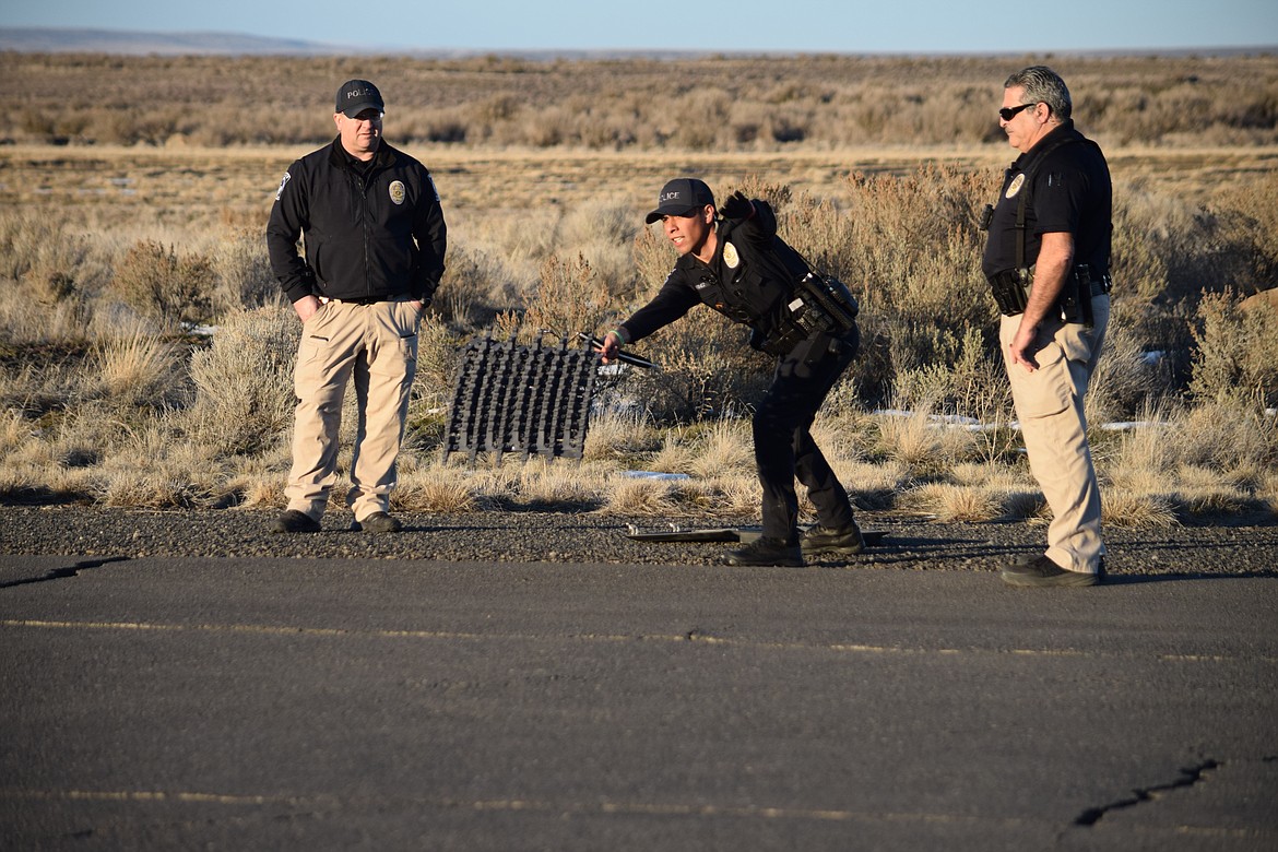 Quincy Police Officer Jerry Martinez (center) throws a spike strip — spikeless for training purposes — as Detective Damon Powell (left) and Officer Sal Mancini (right) watch.