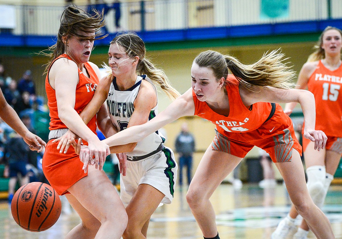 Flathead's Avery Chouinard (13) and Kennedy Moore (14) defend as Glacier's Kiera Sullivan (5) drives into the lane at Glacier High School on Thursday, Feb. 17. (Casey Kreider/Daily Inter Lake)