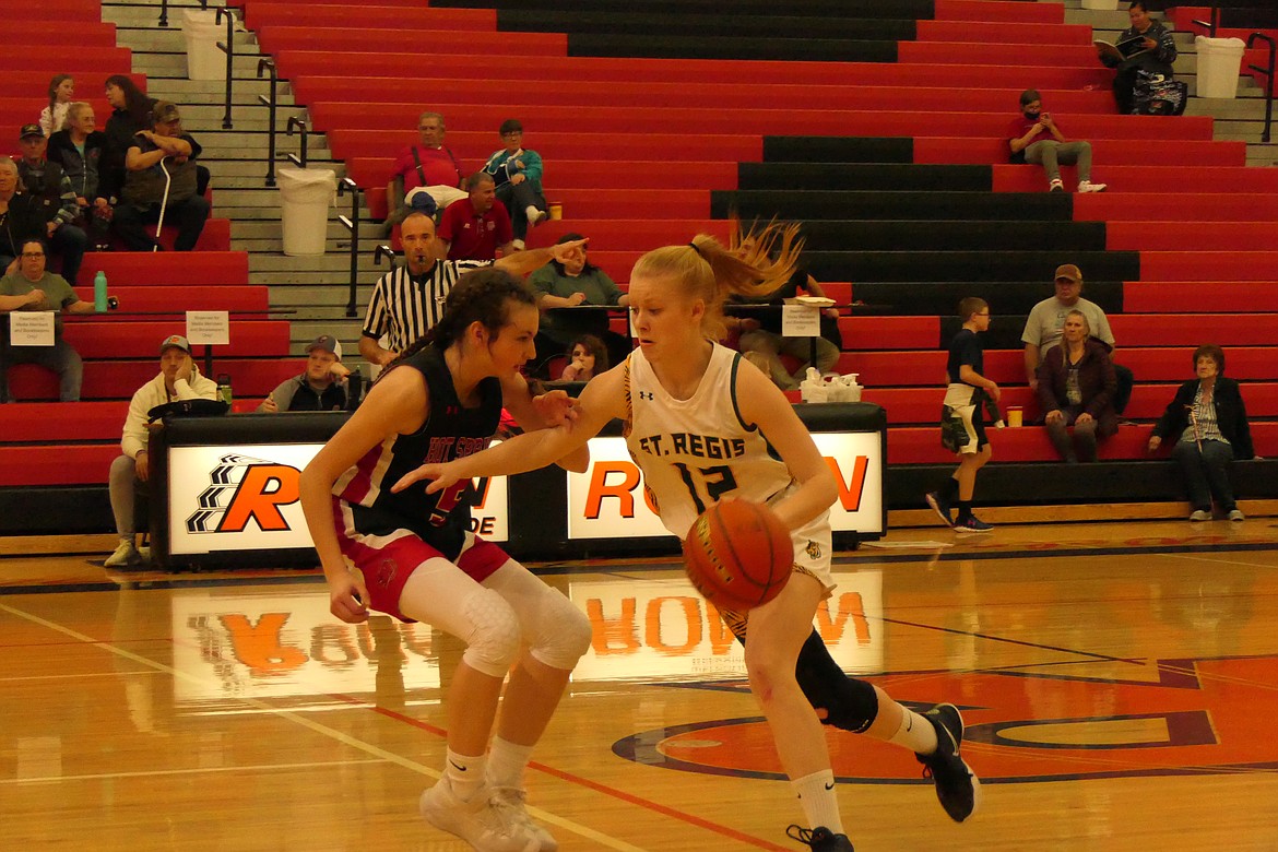 Hot Springs eighth grader Kara Christensen tries to defend St. Regis guard Macy Hill (12) as she drives to the basket Saturday evening in the consolation final of the Western 14C District tourney in Ronan.  (Chuck Bandel/MI-VP)