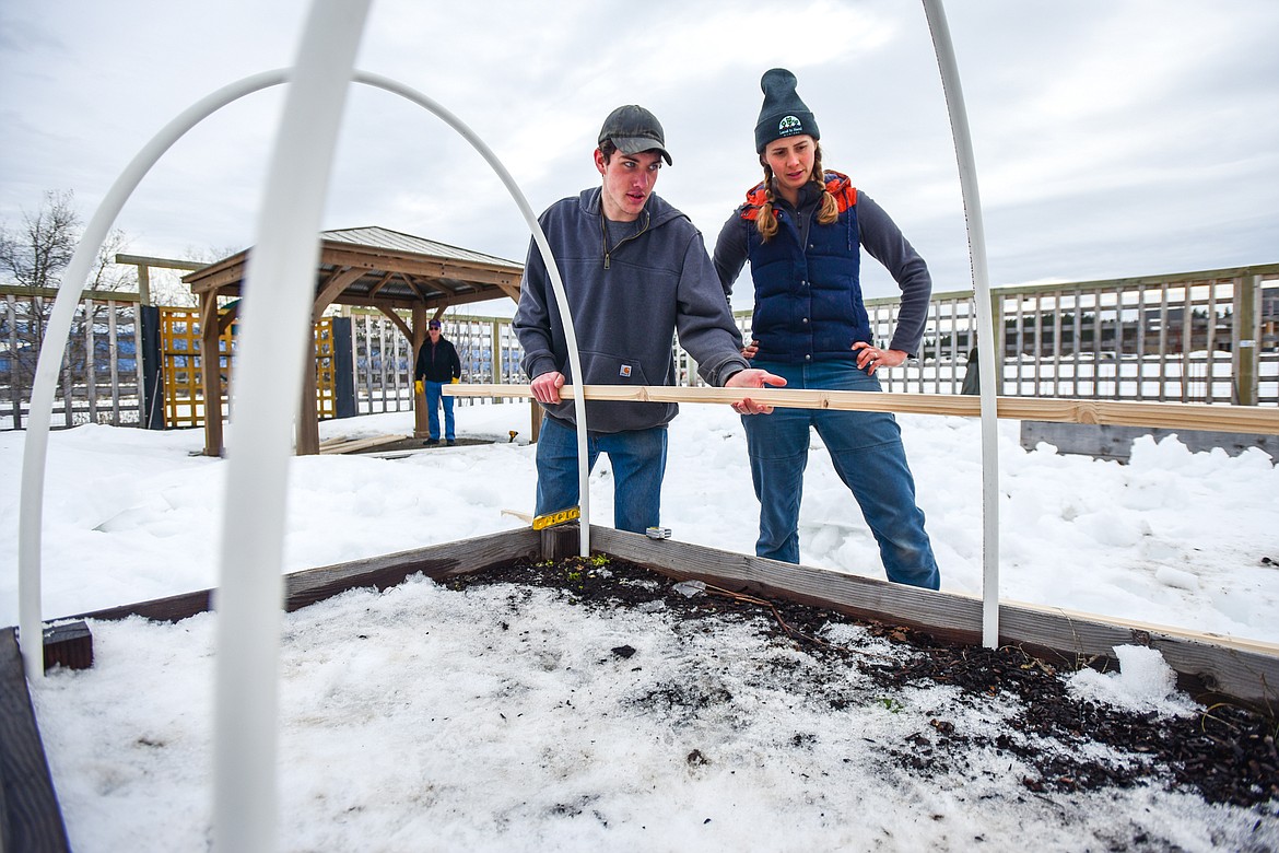 Colton Henriksson, from Boy Scout Troop 1901, and Whitney Pratt, with Land to Hand, measure for the outer frame of one of the greenhouses the scouts were building on the garden boxes at Logan Health Whitefish's Planetree Garden on Saturday, Feb. 19. (Casey Kreider/Daily Inter Lake)