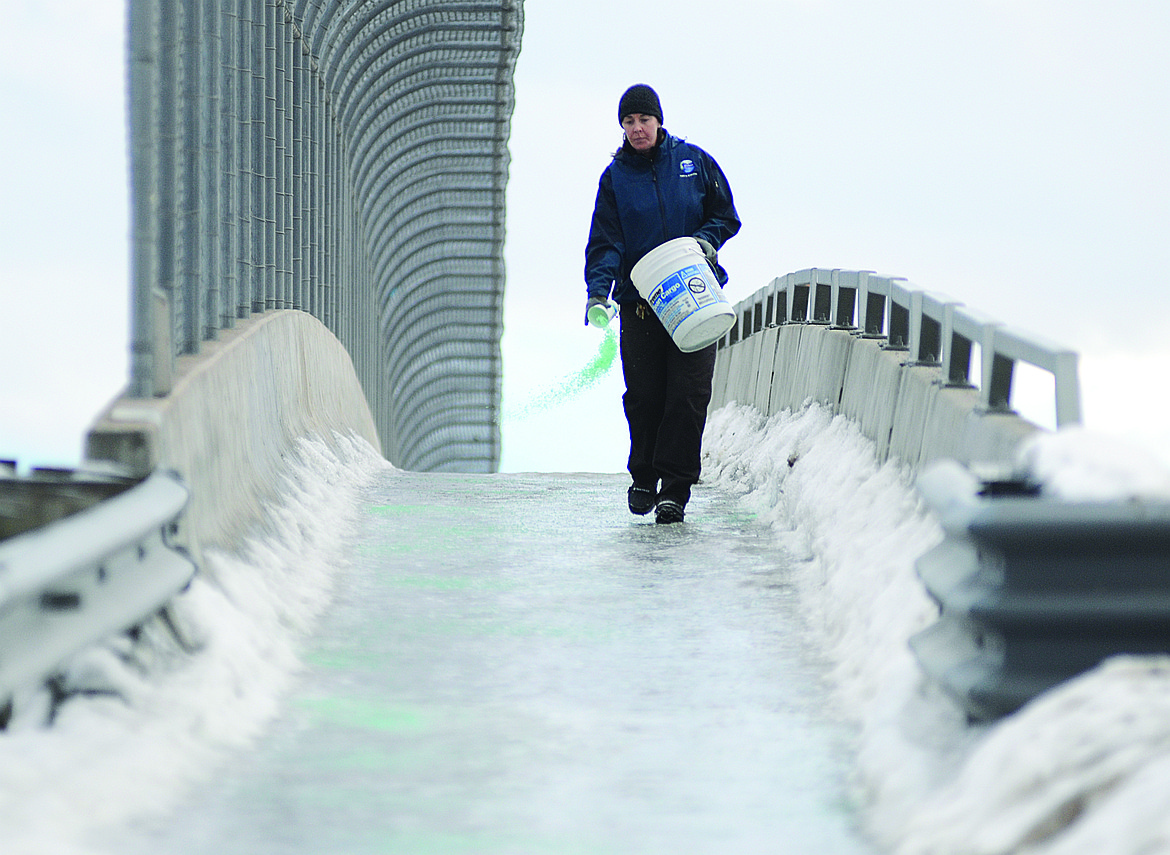 City of Whitefish employee Jen Sybrant spreads ice melt on the viaduct walkway in this 2014 file photo. (Whitefish Pilot FILE)