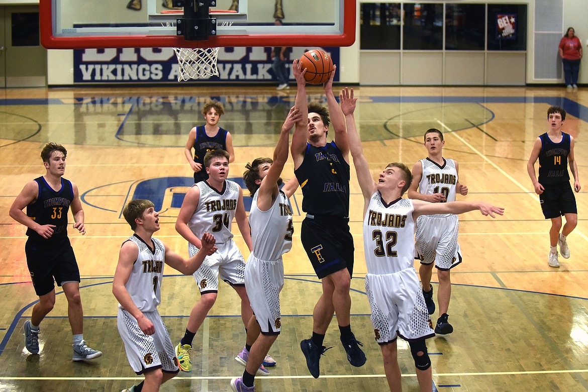 Thompson Falls guard Nathan Schraeder goes to the basket against Troy defenders Paxton Fisher (2) and Michael Foote (32) during action against Troy at the District 7B Tournament in Bigfork Thursday.