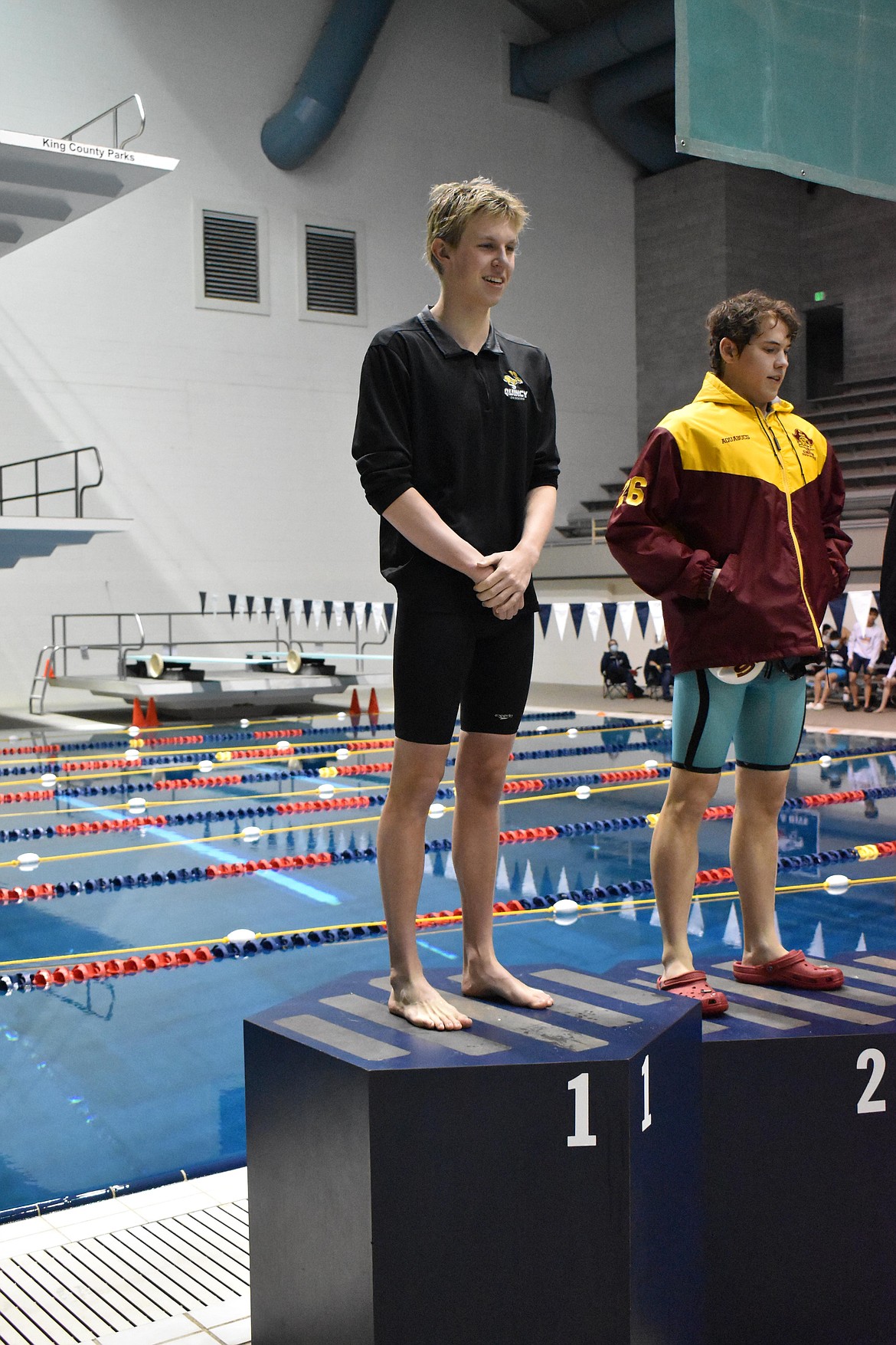 Quincy High School junior Trenten Calloway stands on the podium in the first place spot for winning the 100-yard butterfly event at the state competition.