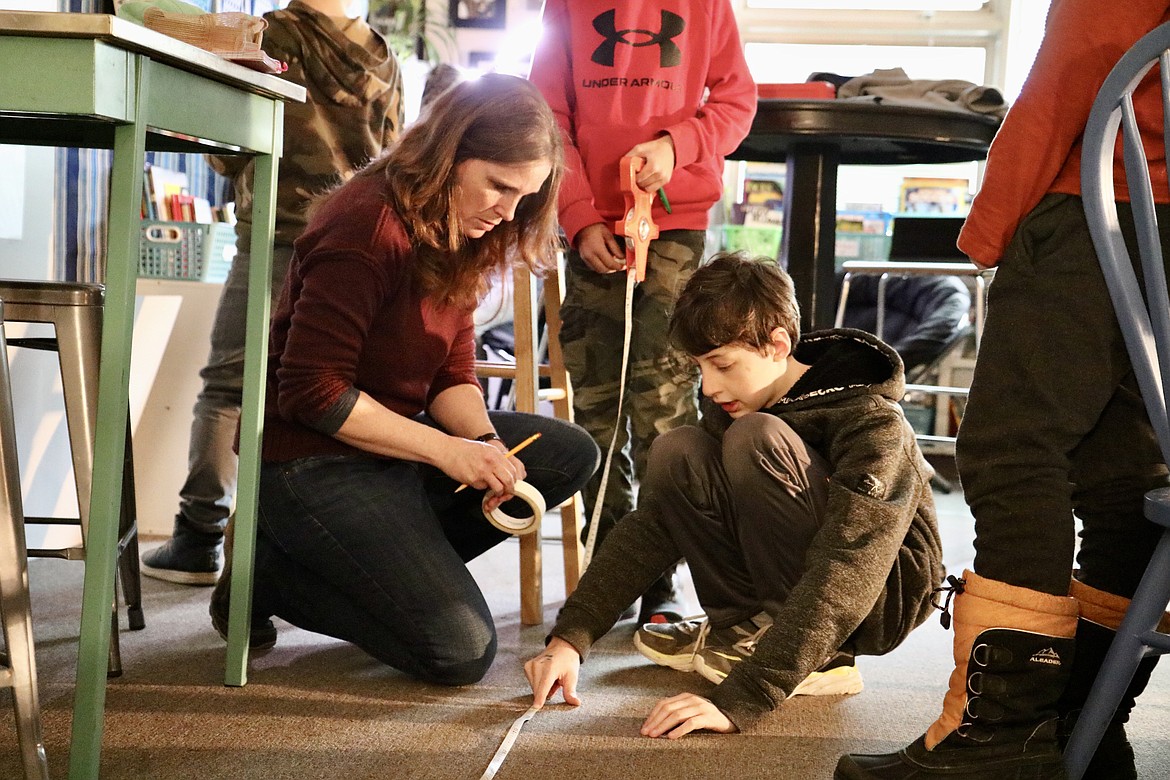 Courtney Greene, a fifth-grade teacher at Fernan STEM Academy, assists fifth-grader Roman Lavrador in an experiment to prove that the apparent brightness of a star is affected by distance from it. HANNAH NEFF/Press