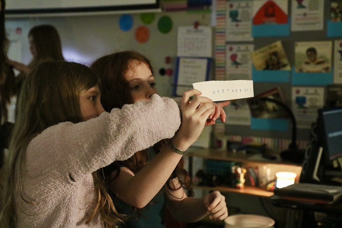 From left, fifth graders Cora Brozek and Kenzi Amen work on an experiment to prove that the apparent brightness of a star is affected by distance at Fernan STEM Academy on Tuesday. HANNAH NEFF/Press