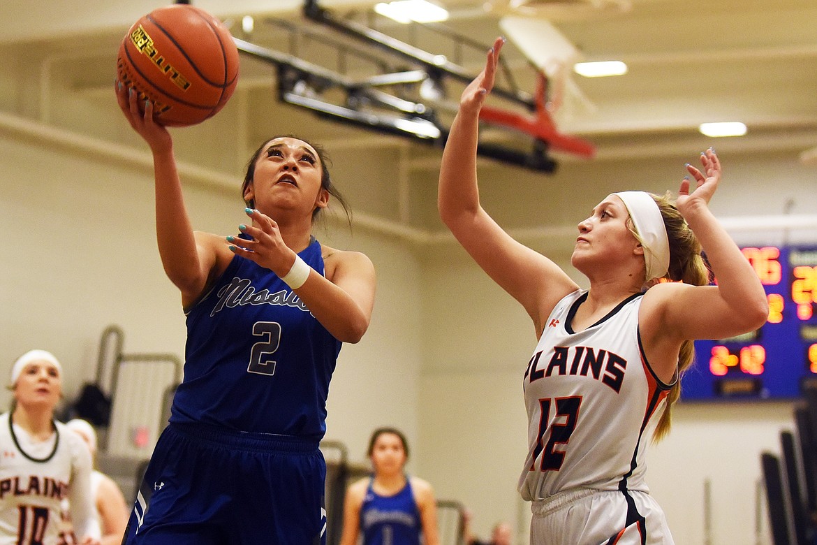 Mission's Kooper Page takes the ball to the basket against Plains defender Kaylah Standeford during action at the District 7B basketball tournament in Bigfork. (Jeremy Weber/Daily Inter Lake)