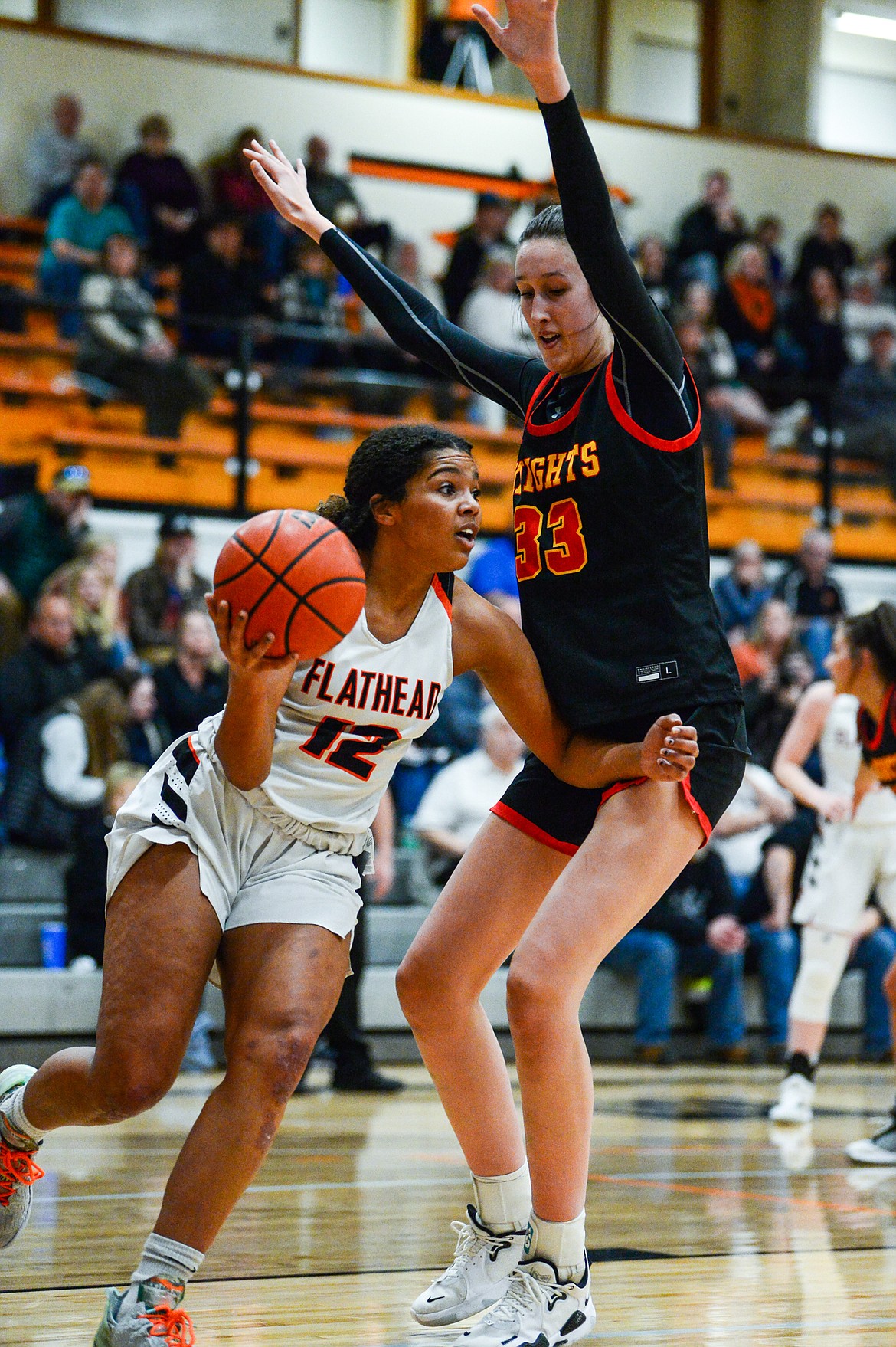 Flathead's Akilah Kubi (12) looks for a passing lane under the basket guarded by Missoula Hellgate's Alex Covill (33) at Flathead High School on Thursday, Feb. 24. (Casey Kreider/Daily Inter Lake)