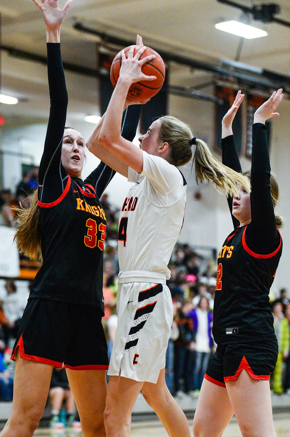 Flathead's Kennedy Moore (14) looks to shoot between Missoula Hellgate defenders Alex Covill (33) and Bailee Sayler (22) at Flathead High School on Thursday, Feb. 24. (Casey Kreider/Daily Inter Lake)