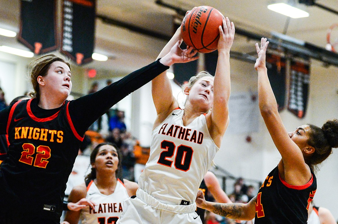 Flathead's Tali Miller (20) fights for a rebound between Missoula Hellgate's Bailee Sayler (22) and Keke Davis (24) at Flathead High School on Thursday, Feb. 24. (Casey Kreider/Daily Inter Lake)