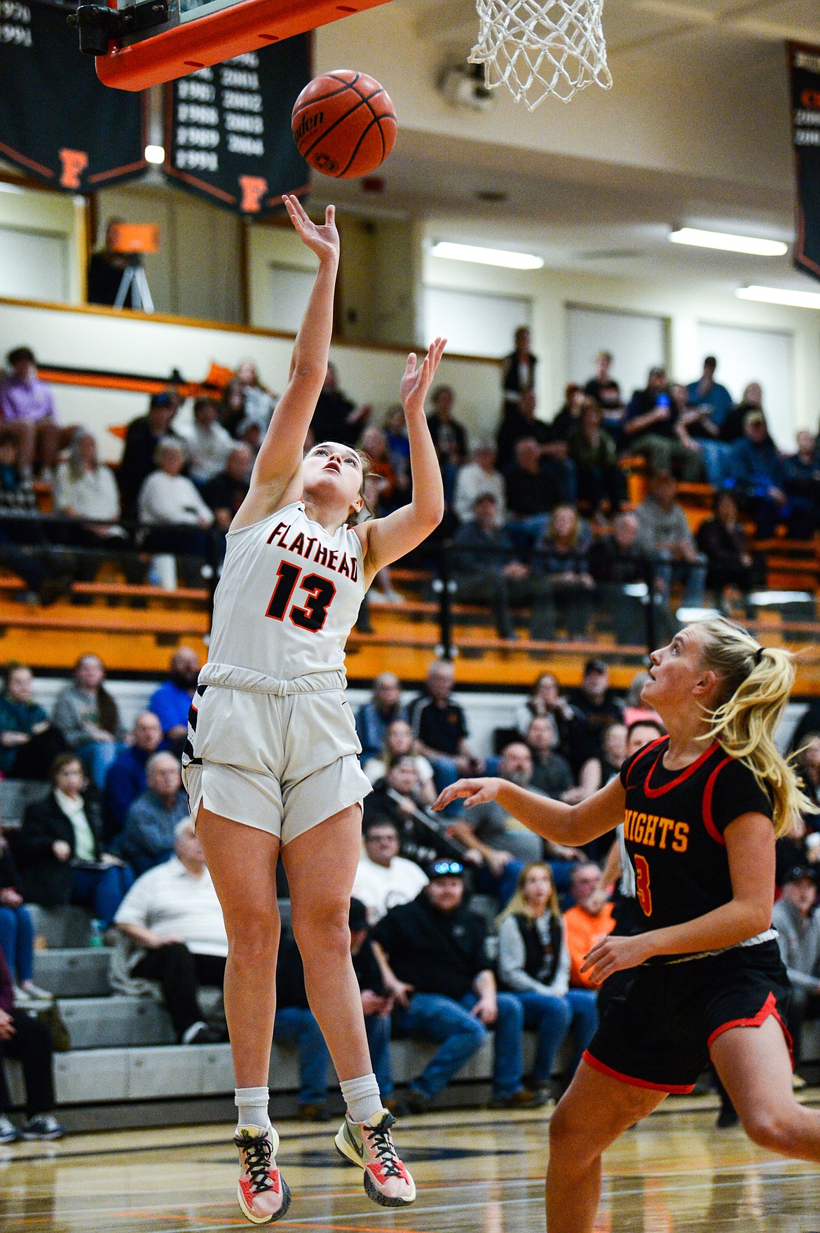 Flathead's Avery Chouinard (13) goes to the basket in front of MIssoula Hellgate's Addy Heaphy (3) at Flathead High School on Thursday, Feb. 24. (Casey Kreider/Daily Inter Lake)