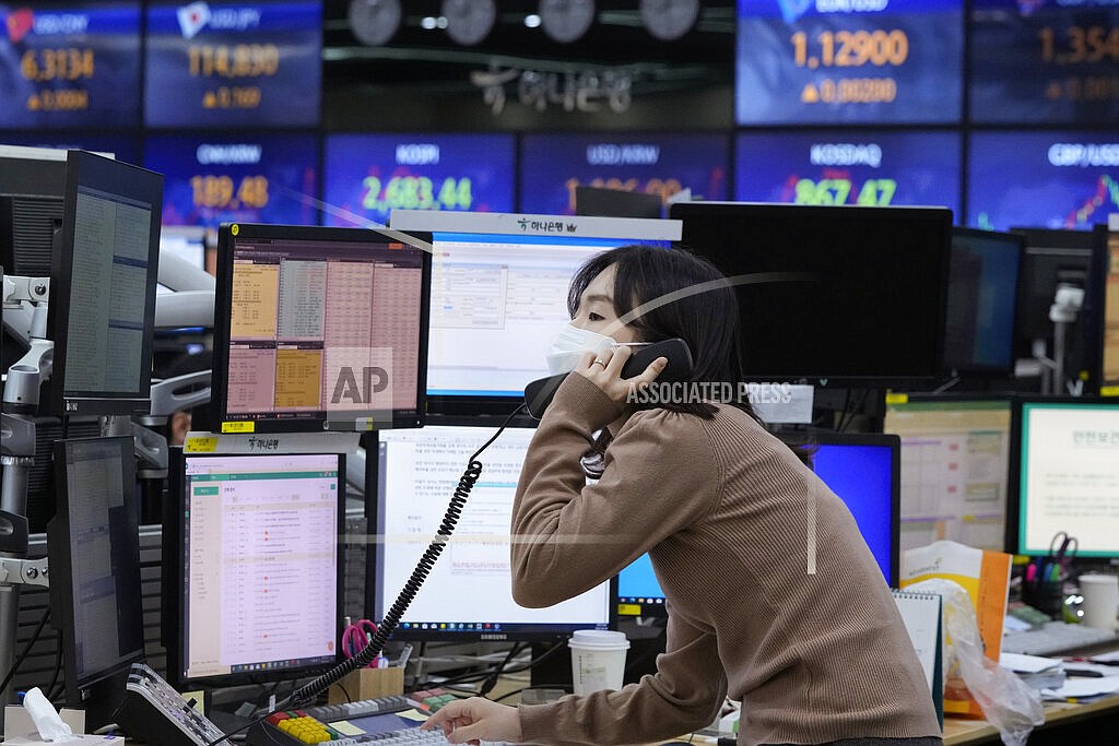 A currency trader talks on the phone at the foreign exchange dealing room of the KEB Hana Bank headquarters in Seoul, South Korea, Thursday, Feb. 24, 2022. Just what a vulnerable world economy didn’t need — a conflict that accelerates inflation, rattles markets and portends trouble for everyone from European consumers to indebted Chinese developers and families in Africa that are enduring soaring food prices. Russia’s attack on Ukraine and retaliatory sanctions from the West may not portend another global recession. (AP Photo/Ahn Young-joon)