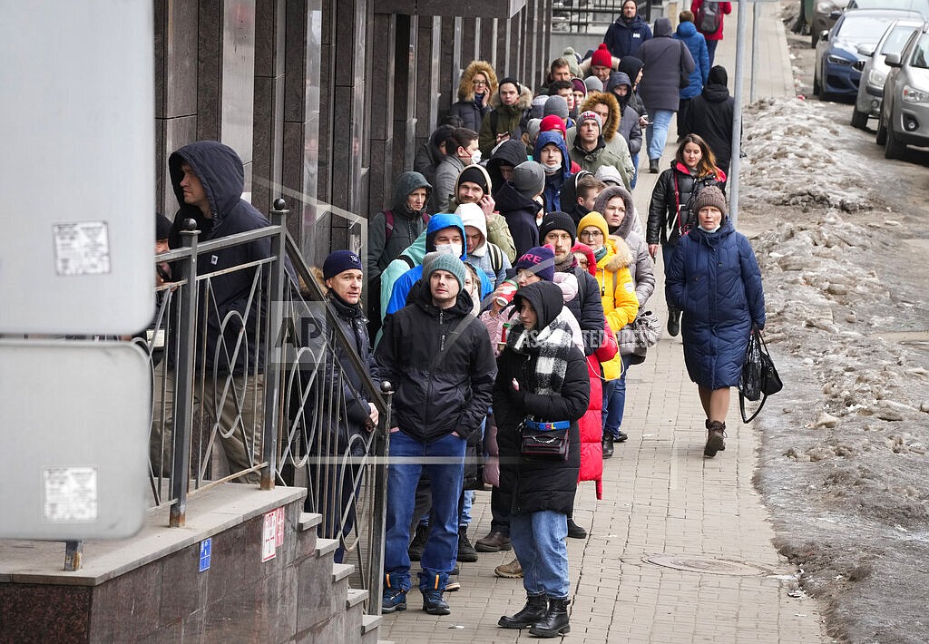 People stand in line to withdraw U.S. dollars and Euros from an ATM in St. Petersburg, Russia, Friday, Feb. 25, 2022. Ordinary Russians faced the prospect of higher prices and crimped foreign travel as Western sanctions over the invasion of Ukraine sent the ruble plummeting, leading uneasy people to line up at banks and ATMs on Monday in a country that has seen more than one currency disaster in the post-Soviet era. (AP Photo/Dmitri Lovetsky)