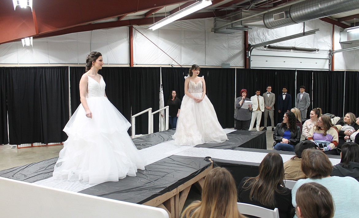 Megan Washburn, left, and Elizabeth Maden take their turns on the runway at the Enchanting Bridal Show fashion show Saturday.
