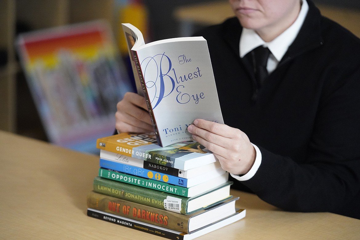 Amanda Darrow, director of youth, family and education programs at the Utah Pride Center, poses with books, including "The Bluest Eye," by Toni Morrison, that have been the subject of complaints from parents in Salt Lake City on Dec. 16, 2021. (AP Photo/Rick Bowmer, File)