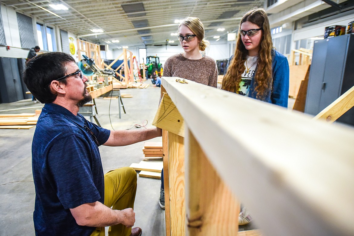 Instructor Brian Bay gives some advice to Glacier High School juniors Faith Jensen and Rachelle Becker as they work on the outer frame of their shed at the H.E. Robinson Agricultural Education Center in Kalispell on Wednesday, March 2. (Casey Kreider/Daily Inter Lake)