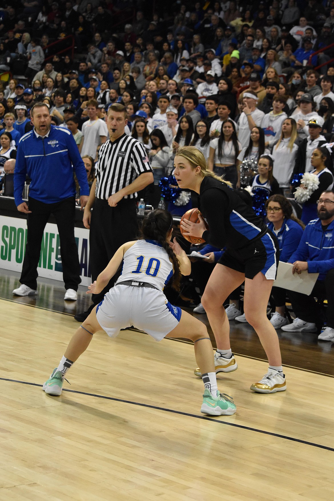 Warden High School senior Jaryn Madsen (5) looks to her teammate as a Colfax player guards her. To the left, Warden head coach and father Josh Madsen, watches along with a referee.