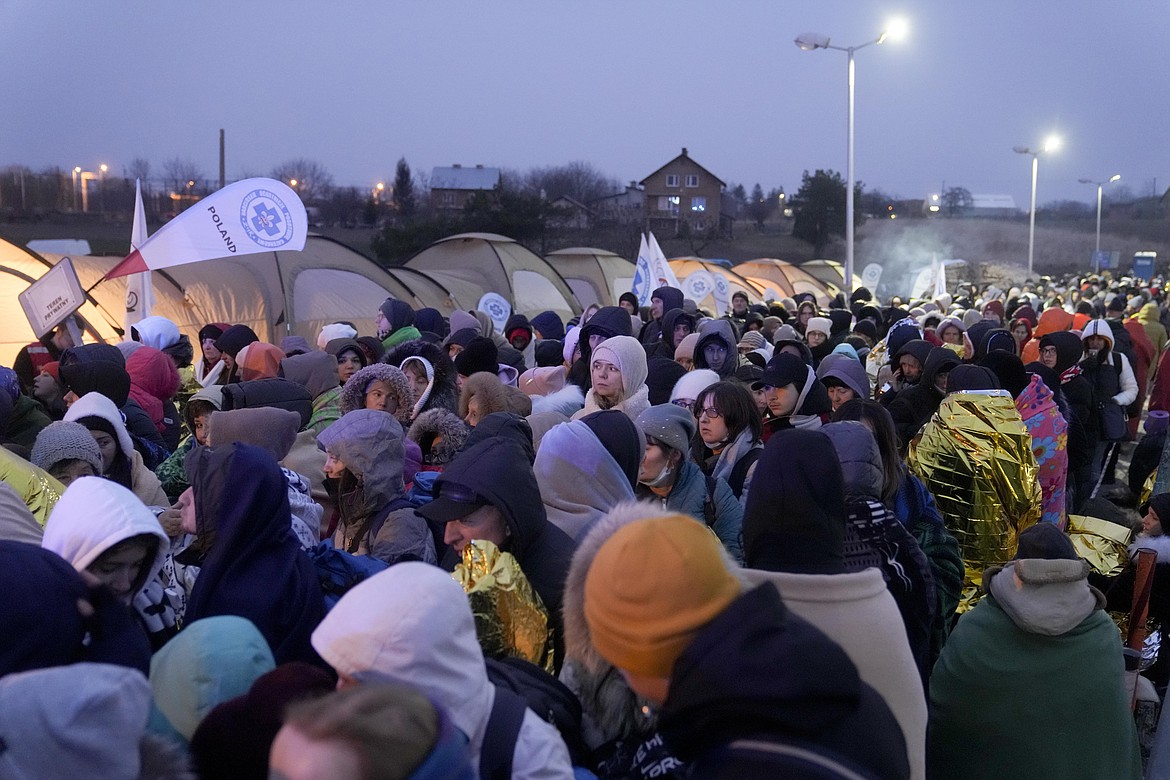 Refugees wait in a crowd for transportation after fleeing from the Ukraine and arriving at the border crossing in Medyka, Poland, Monday, March 7, 2022. Hundreds of thousands of Ukrainian civilians attempting to flee to safety Sunday were forced to shelter from Russian shelling that pummeled cities in Ukraine’s center, north and south. (AP Photo/Markus Schreiber)