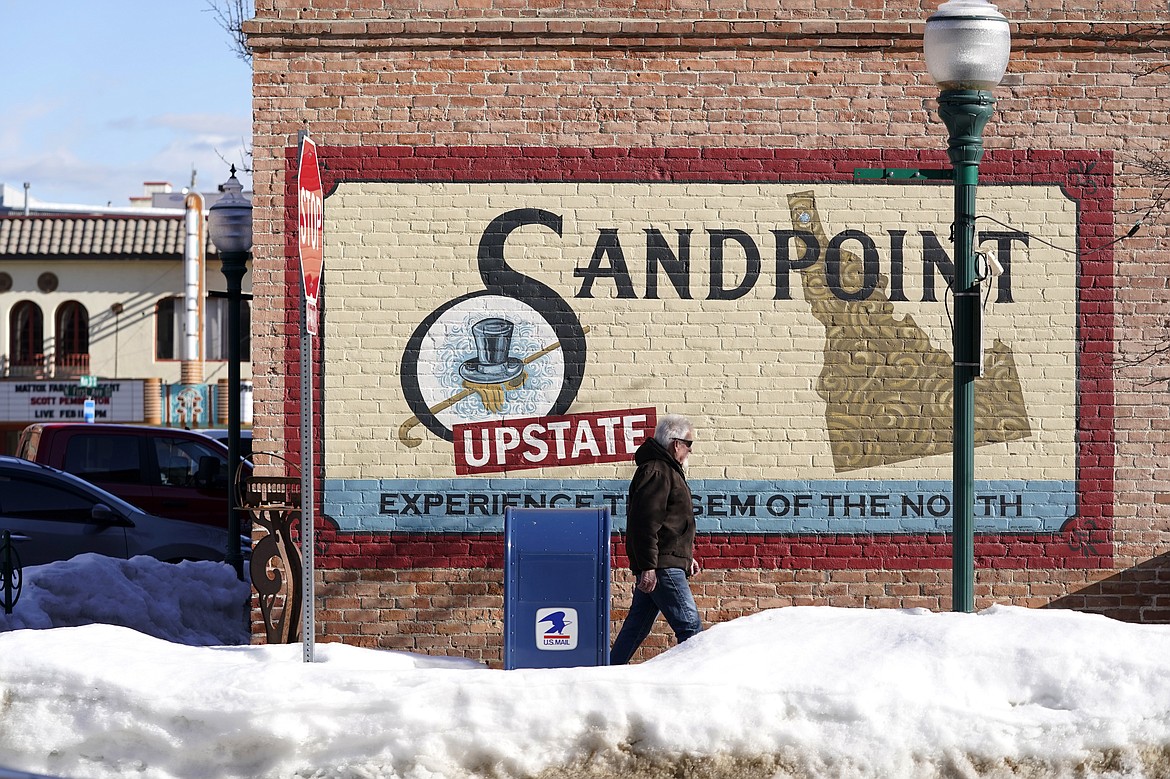 A pedestrian walks past a mural, Monday, Feb. 7, 2022, in downtown Sandpoint, Idaho. The Mayor of Sandpoint and many residents worry that the trend of a growing number of real estate companies advertising to conservatives that they can help people move out of liberal bastions like Seattle and San Francisco and find homes in places like rural Idaho is not good for their community.