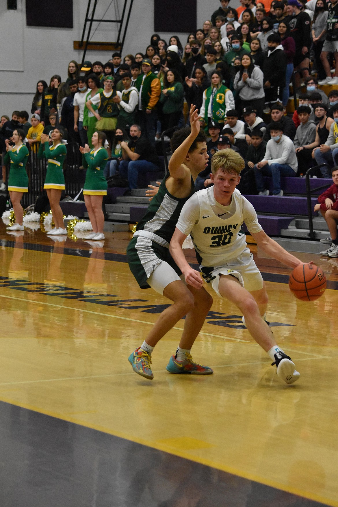 Quincy High School senior Aidan Heikes (30) drives past Chelan High School senior Nate Harding (1) toward the hoop on Jan. 25.