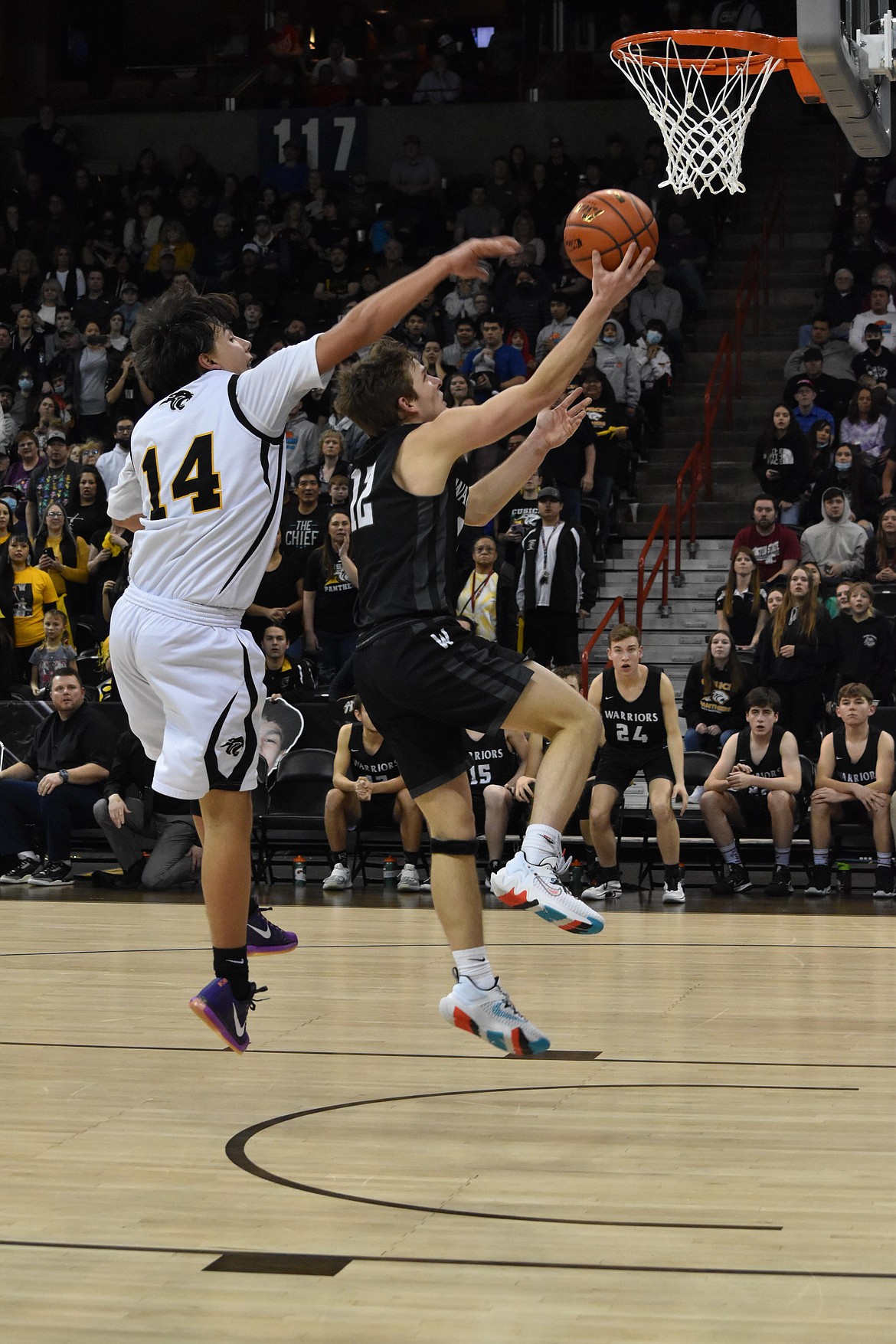 ACH senior Dane Isaak (12) goes in for a layup as Cusick senior Kyden Nomee (14) attempts to swat the ball out of his hands on March 5 at the Spokane Arena.