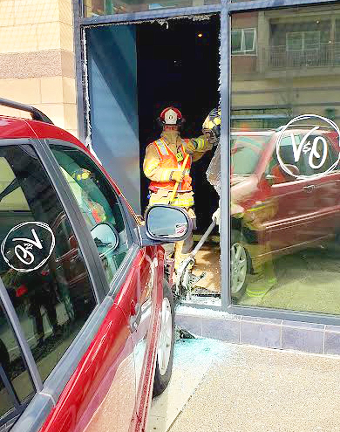 Coeur d'Alene Fire Department Capt. Josh Sutherland and Firefighter Eric McAuliff remove broken glass from the front of Vine and Olive Eatery & Wine Bar on Monday.