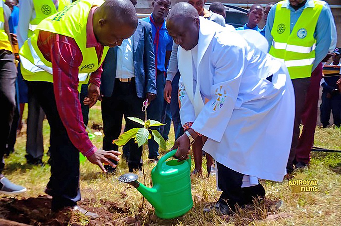 A priest blesses a tree planting during an event to honor participants, guests, and the contributors who helped complete an abandoned dorm and replaced possessions lost in a fire.