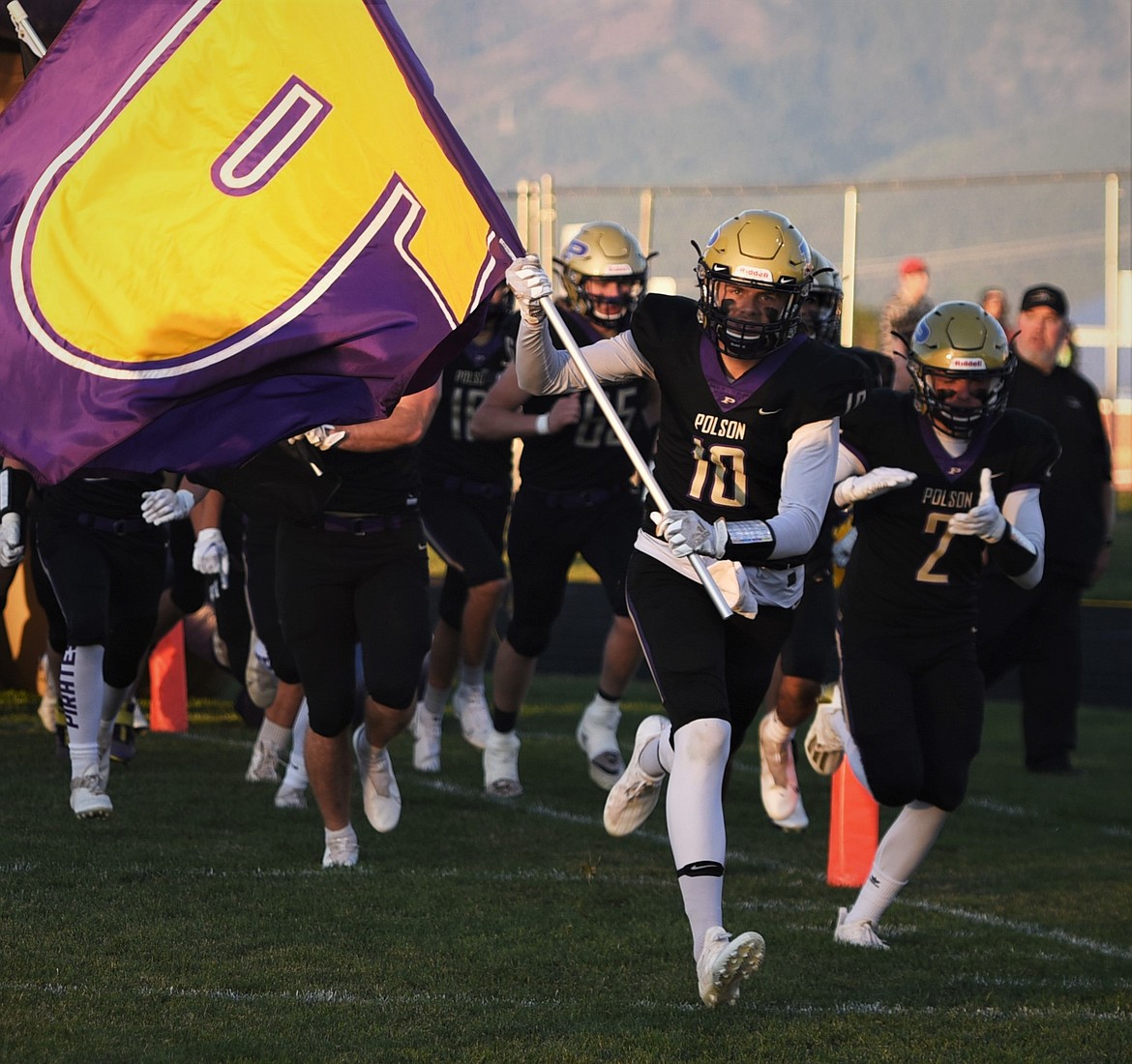 Colton Graham carries the Polson flag as the Pirates take the field for a home football game. (Scot Heisel/Lake County Leader)