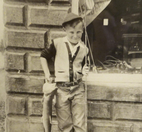 Young Rand Robbin in front of Robbin's mercantile store in Bigfork with a Dolly Varden trout. (Collection of Rand Robbin)