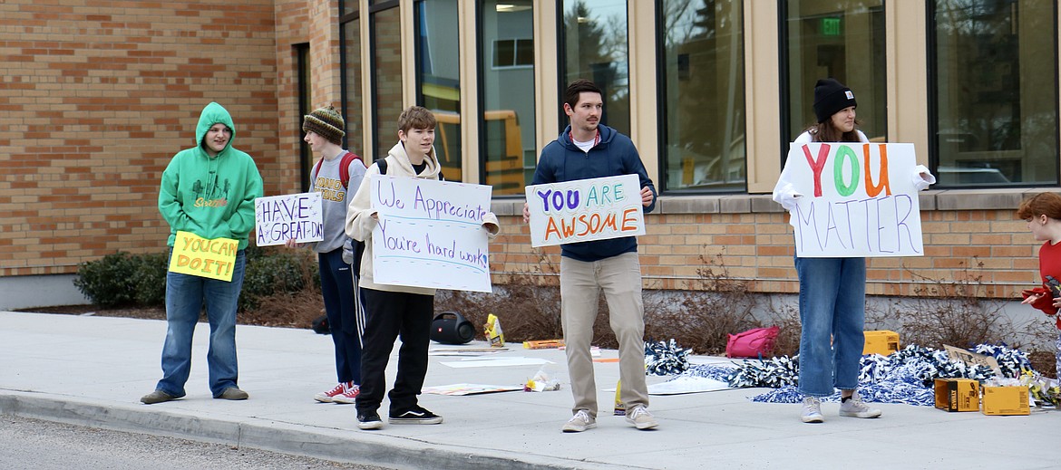 Lakes Middle School Kind Club waved signs and handed out flowers to parents and other drivers as they dropped students off at the school on Thursday morning. From left, Harley Hult, Connor Svanby, Wyatt Crouse, adviser Marcus Ross, and Jonnie Vedder. HANNAH NEFF/Press