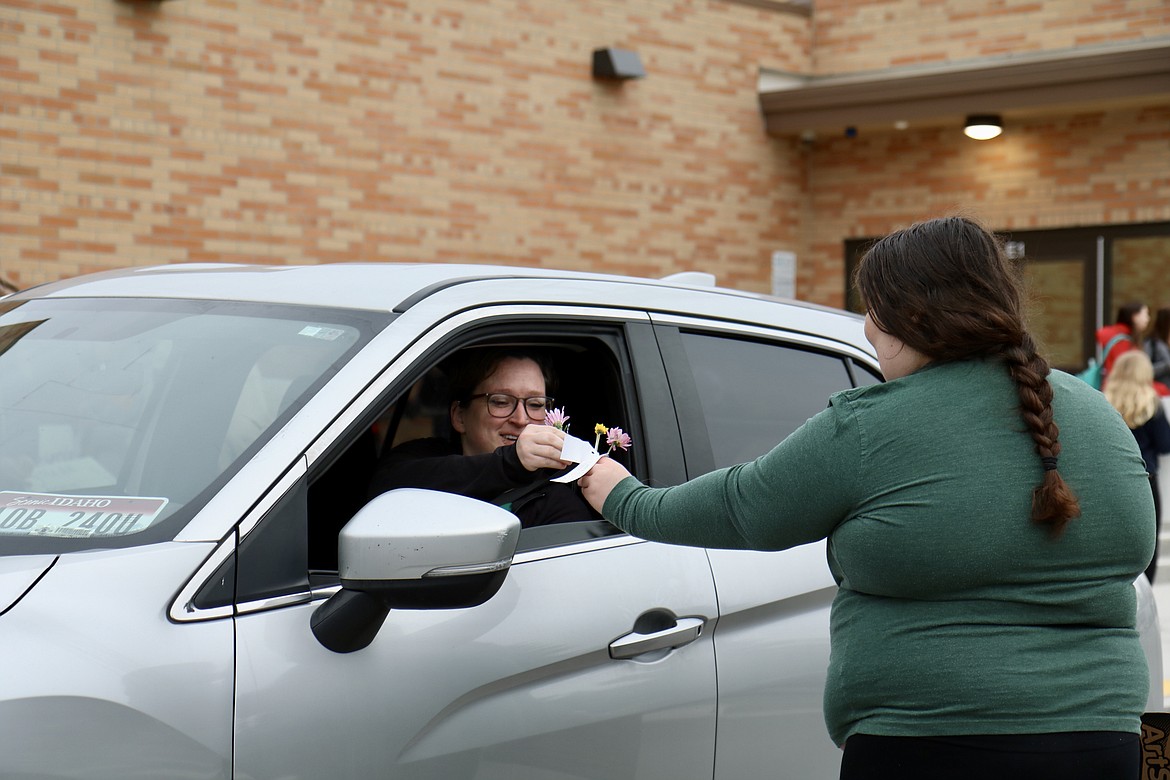 Lakes Middle School parent Rita Waldo receives a flower from student Sadie Daggett, a member of the school's Kind Club on Thursday morning. HANNAH NEFF/Press