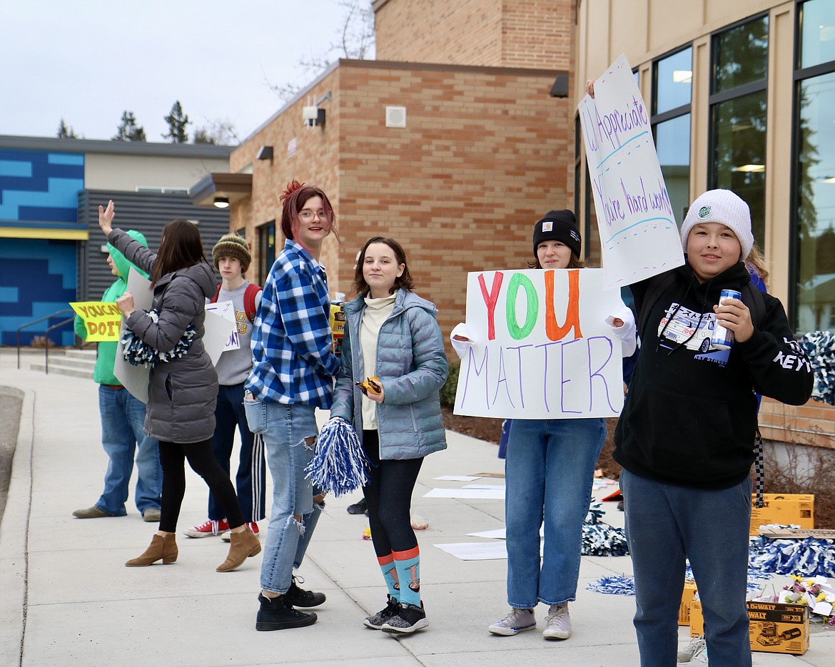 On front right, Lakes Middle School student Aiden Owens holds up a sign outside of the school in Coeur d'Alene on Thursday morning. The school Kind Club waved signs and handed out flowers to parents and other drivers as they dropped students off at the school. HANNAH NEFF/Press