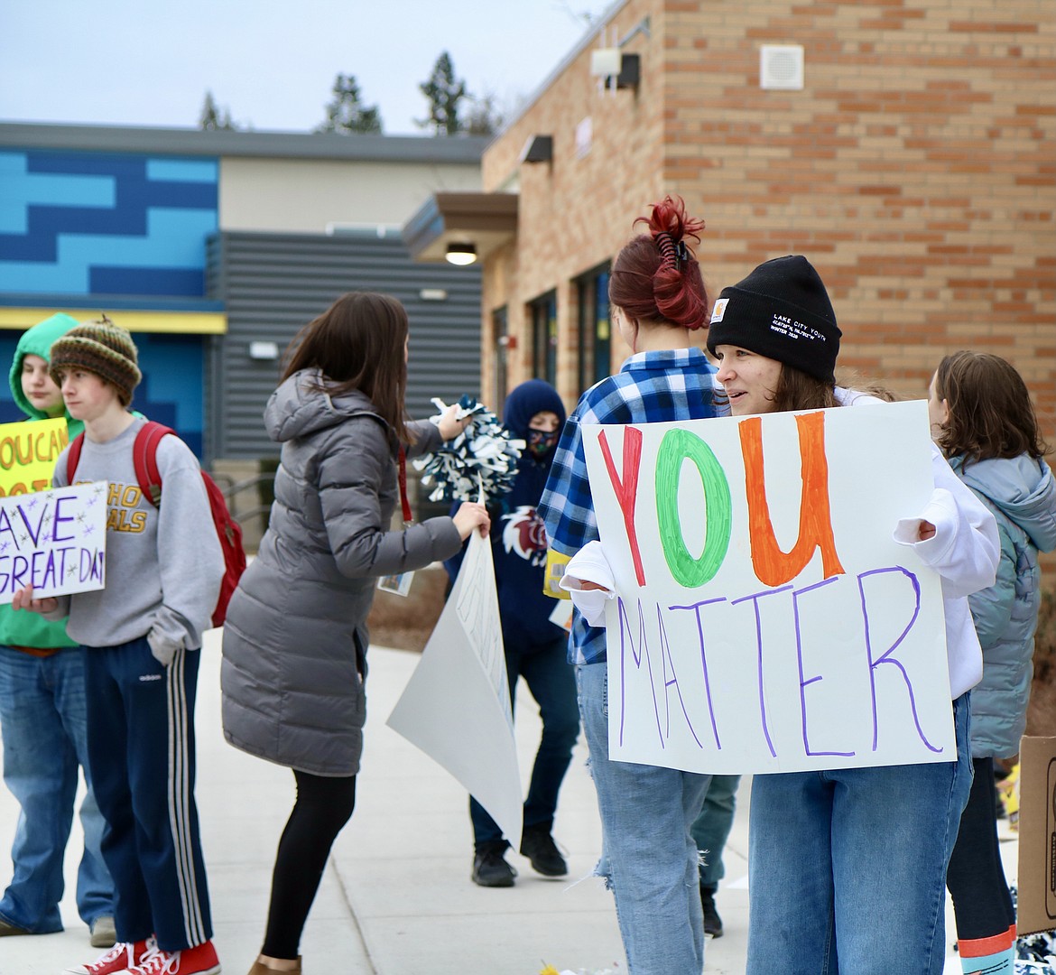 On right in front, eighth grader Jonnie Vedder holds up a sign outside of Lakes Middle School in Coeur d'Alene on Thursday morning. The school Kind Club waved signs and handed out flowers to parents and other drivers as they dropped students off at the school. HANNAH NEFF/Press