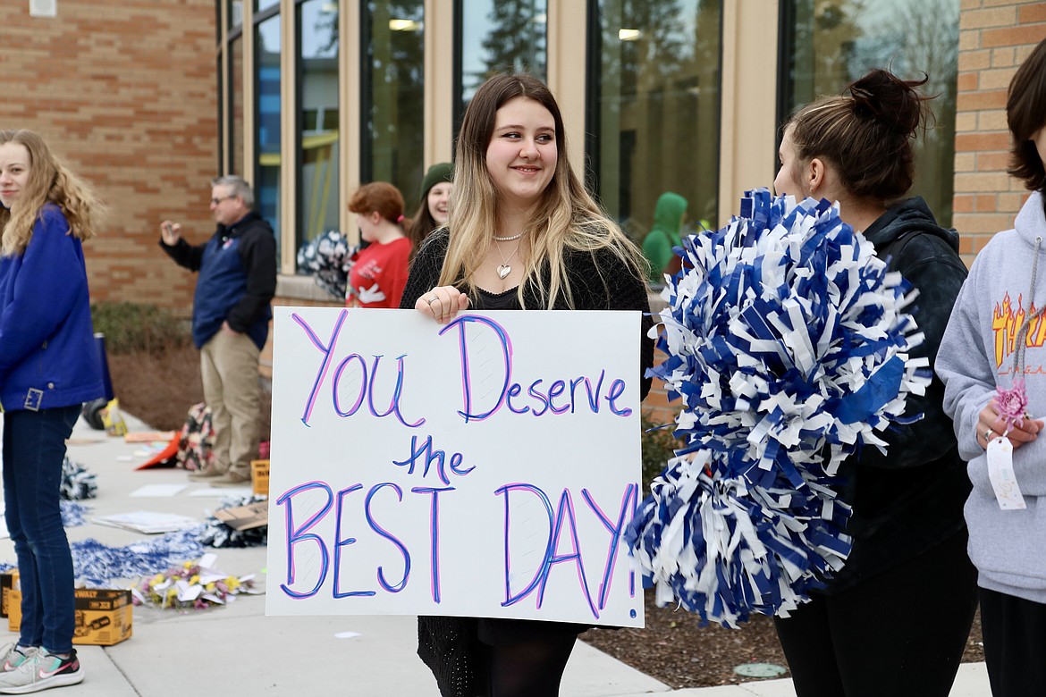 Holding the sign in center, Lakes Middle School student Syringa Kirsch stands outside of the school on Thursday morning. The school Kind Club waved signs and handed out flowers to parents and other drivers as they dropped students off at the school. HANNAH NEFF/Press