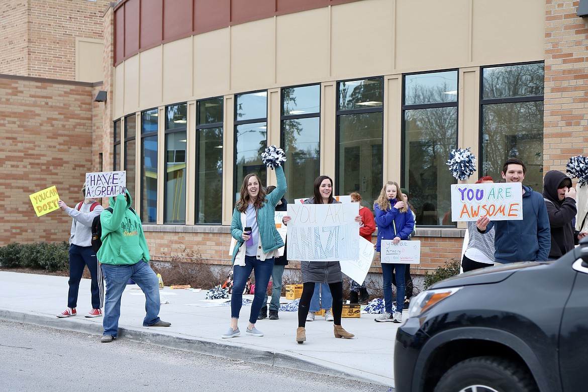 Members of Lakes Middle School Kind Club handed out flowers and waved signs to parents and other drivers as they dropped students off at the school on Thursday morning. HANNAH NEFF/Press