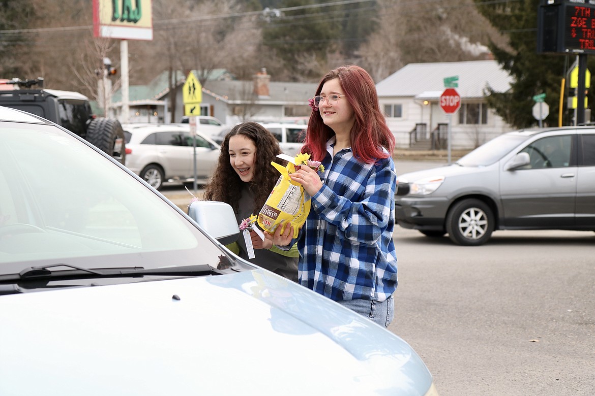 From left, Lakes Middle School students Boston Jones and Ashleigh Sherman Waldo pass out flowers and chocolates to parents and other drivers as they dropped students off at the school. The school kind club greeted drivers with music, pom-poms and signs, showing their appreciation for their parents and other getting them to school. HANNAH NEFF/Press