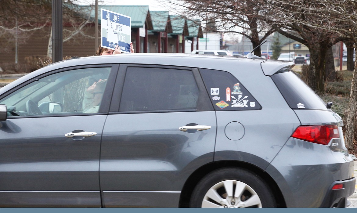 Dorinda Webster holds a sign high during the "Love Lives Here" rally in Hayden on Saturday while a passing driver waves.