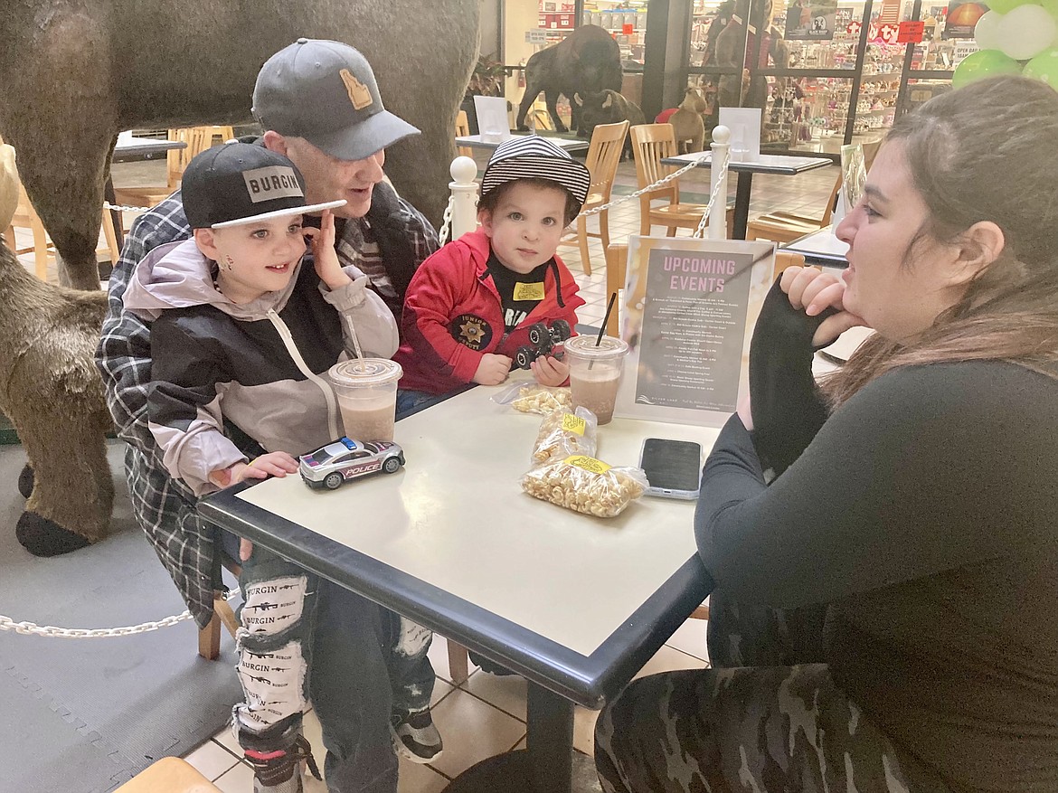 Grandpa Ron Borg holds brothers 3-year-old Lucas and 2-year-old Barrett Burgin while mom Jordan Kaye watches them play at Macadamia Coffee in the Silver Lake Mall on Tuesday morning during the Coffee with a Cop event put on by the Kootenai County Sheriff's Office. HANNAH NEFF/Press