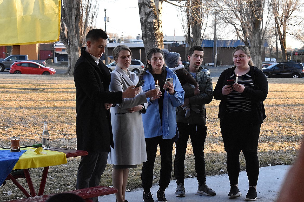 Ruslan Moshniakov (left) and his wife, Anna Moshniakov (second from left) join other Soap Lake community members in singing a few Ukrainian songs at a vigil held at East Beach Park in Soap Lake on March 6. The couple say they are worried about family members who are still in Ukraine and appreciate the support they’ve received from the community.