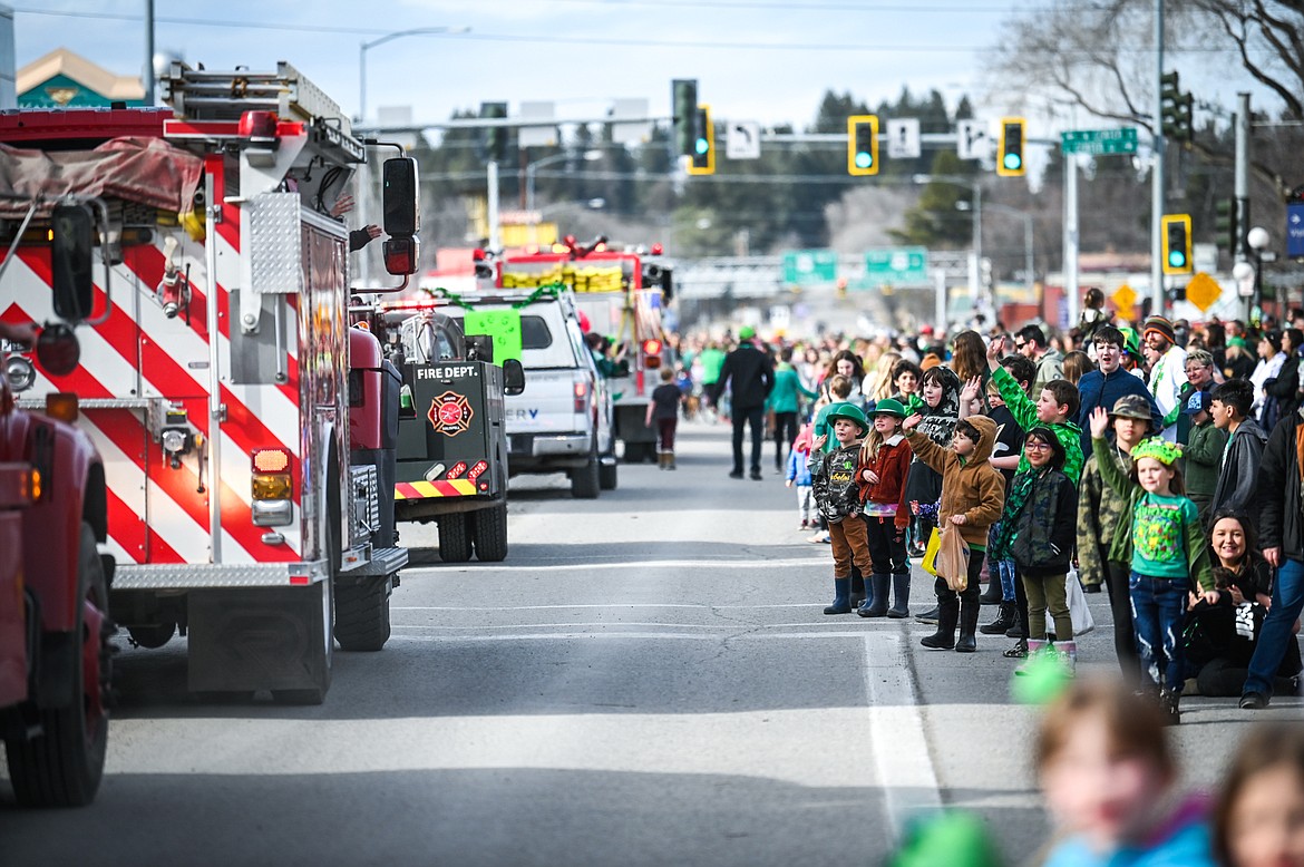 Spectators wave as a line of fire trucks pass during the St. Patrick's Day Parade in Kalispell on Thursday, March 17. (Casey Kreider/Daily Inter Lake)