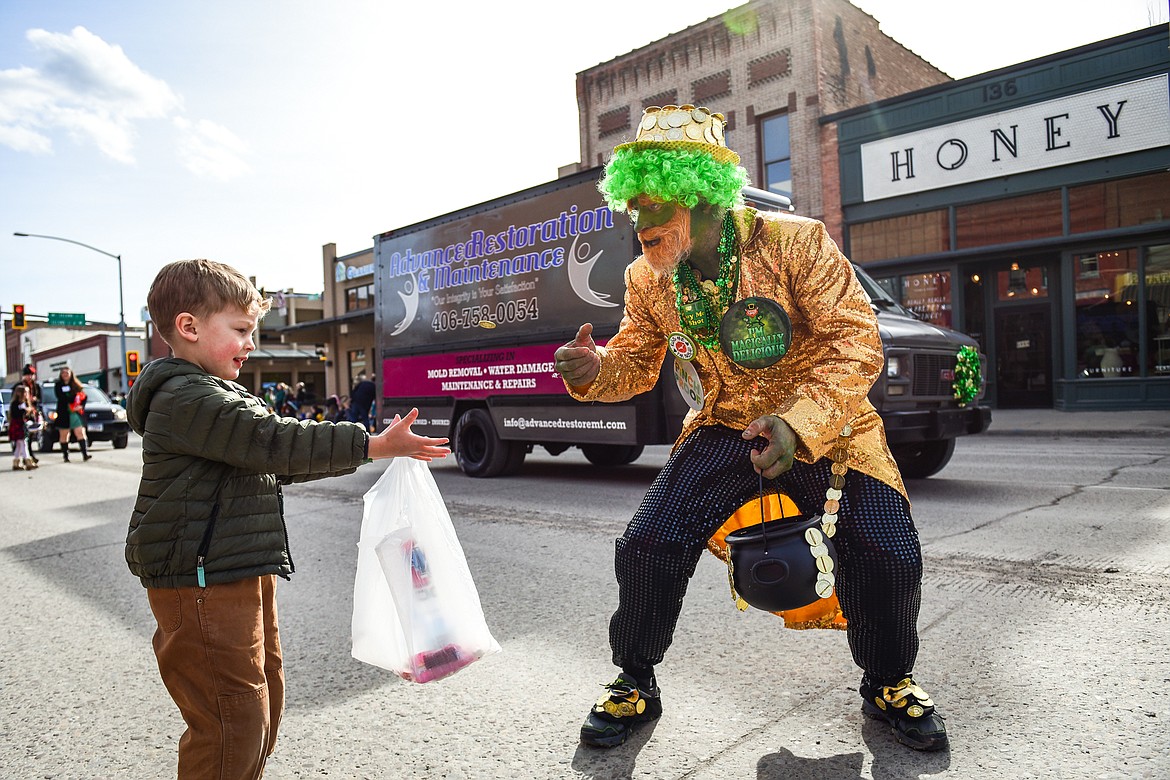 A man dressed as a leprechaun tosses a gold coin to a child during the St. Patrick's Day Parade in Kalispell on Thursday, March 17. (Casey Kreider/Daily Inter Lake)