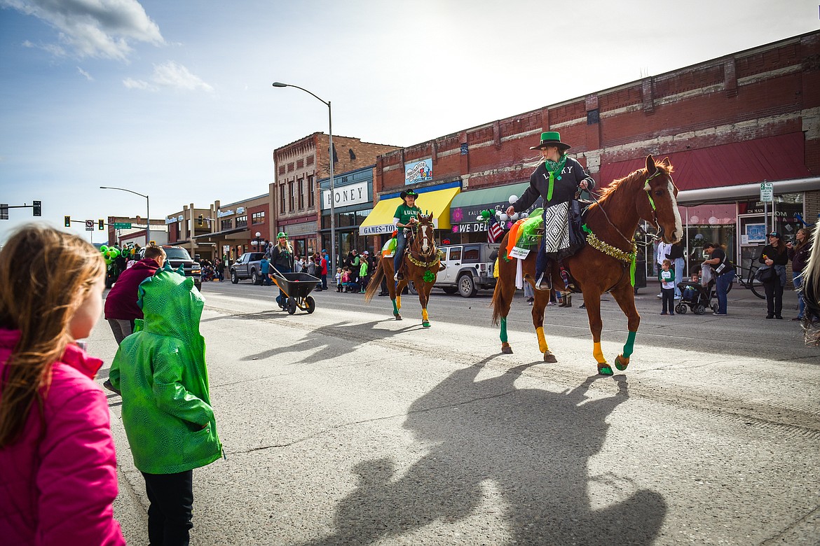 Riders on horses toss candy to spectators during the St. Patrick's Day Parade in Kalispell on Thursday, March 17. (Casey Kreider/Daily Inter Lake)