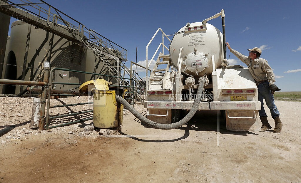 In this April 24, 2015, filephoto, a worker empties oilfield wastewater from a tank truck into storage tanks on Carl and Justin Johnson's ranch near Crossroads, N.M. Labor shortages, supply problems and volatile prices have made oil companies cautious about new drilling even as U.S. politicians push for increased production. (AP Photo/Charlie Riedel, File)